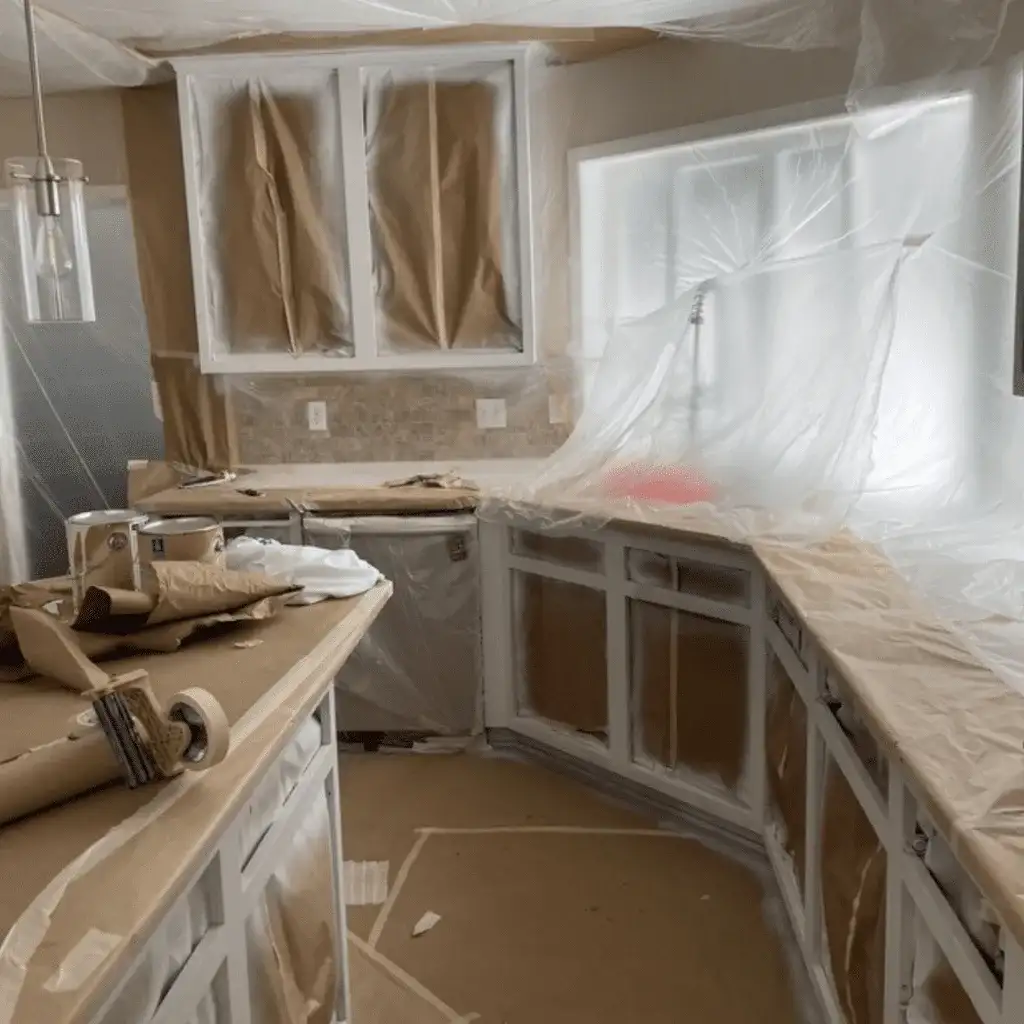 Kitchen wrapped in plastic and paper with the cabinet boxes prepped for paint