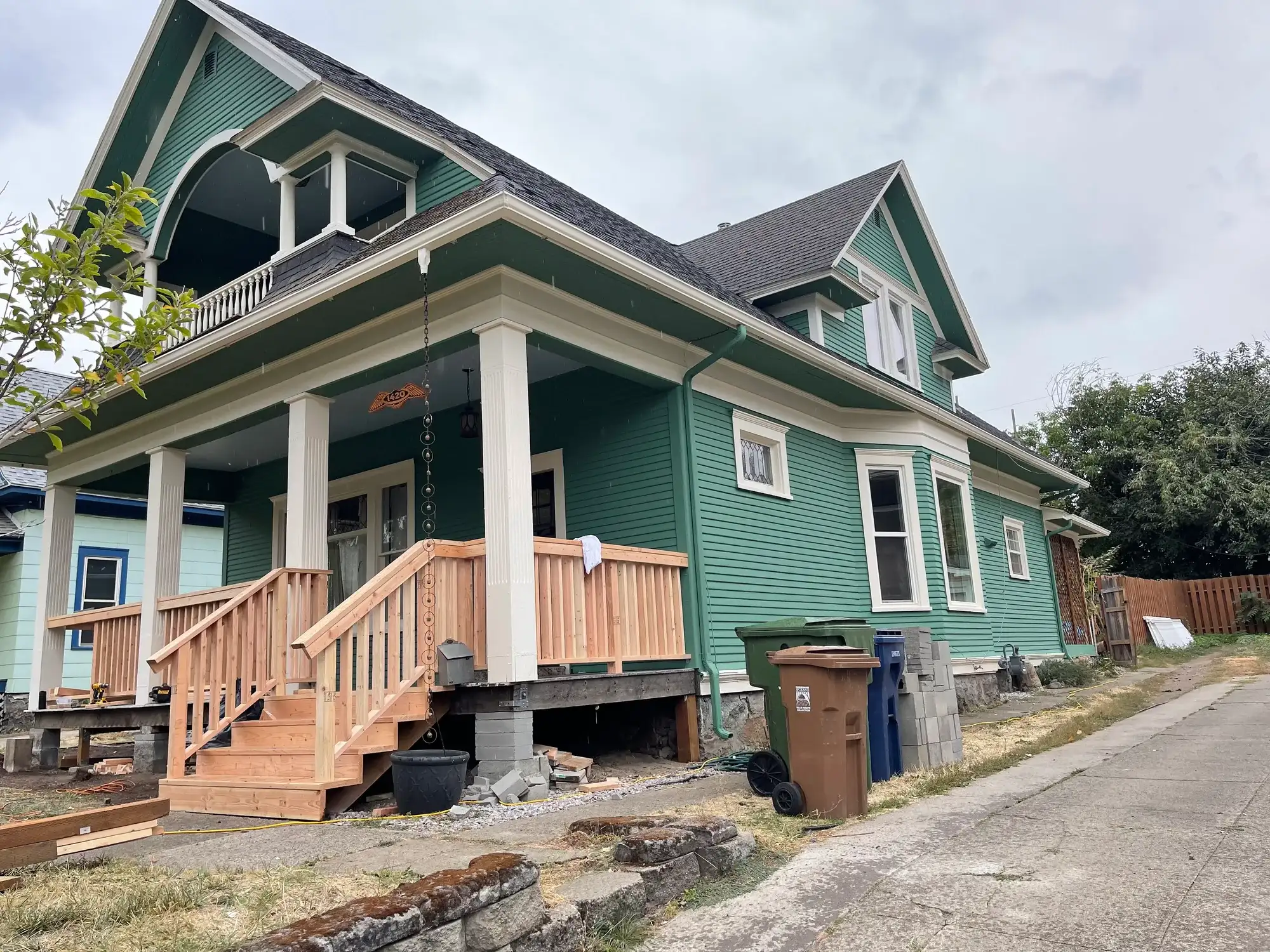 Green Craftsman home with white trim and new wood porch stairs and railings