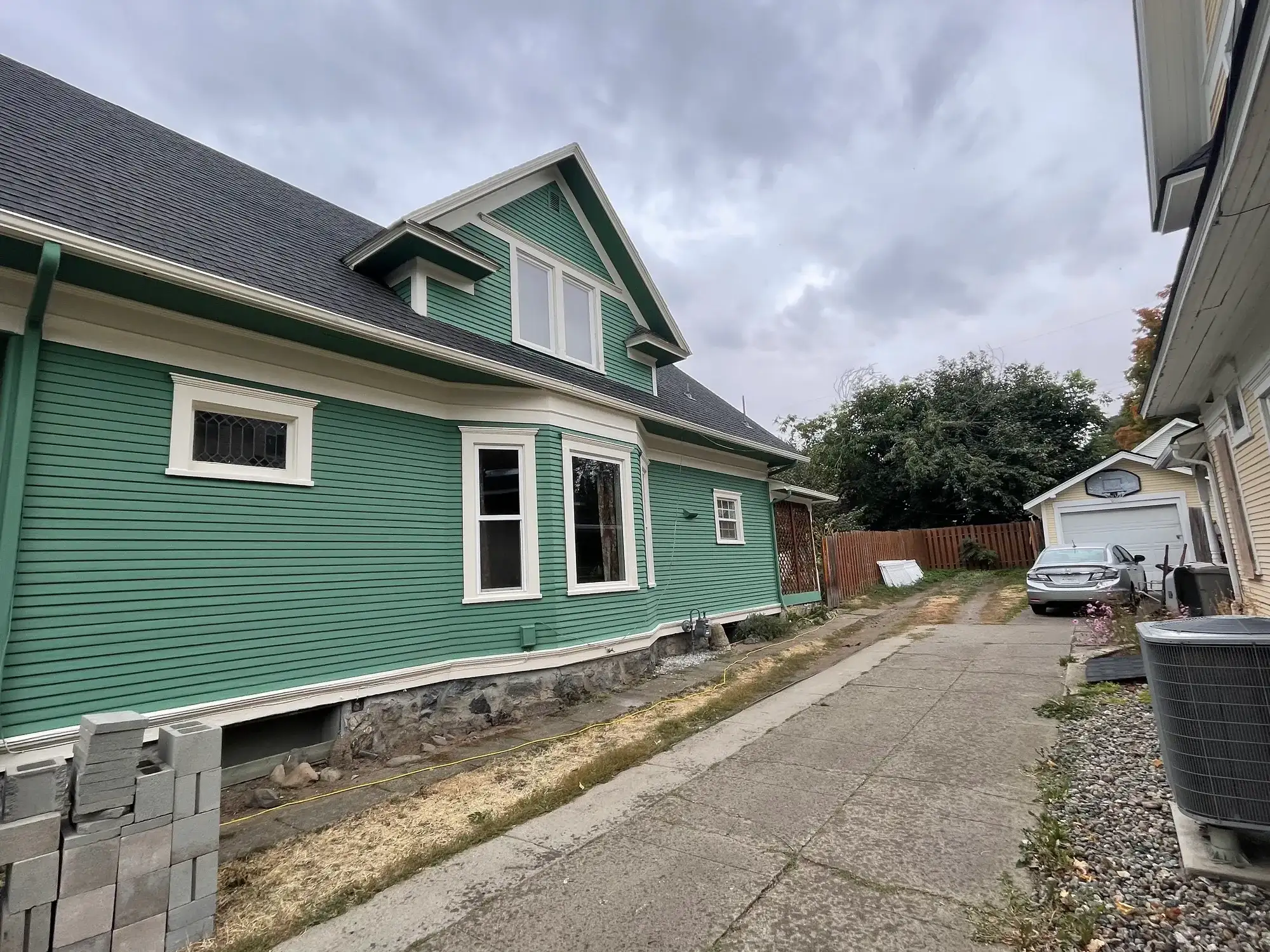 Long side of a green Craftsman home with fresh white window trim