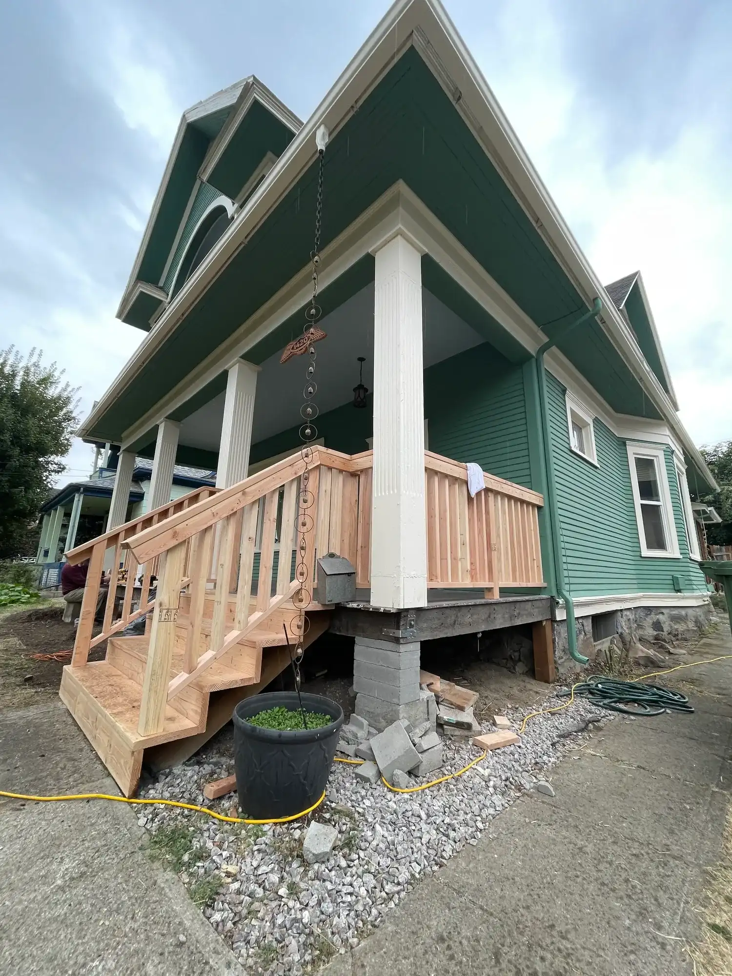 New wood stairs and railings built up to a wraparound porch on a green house