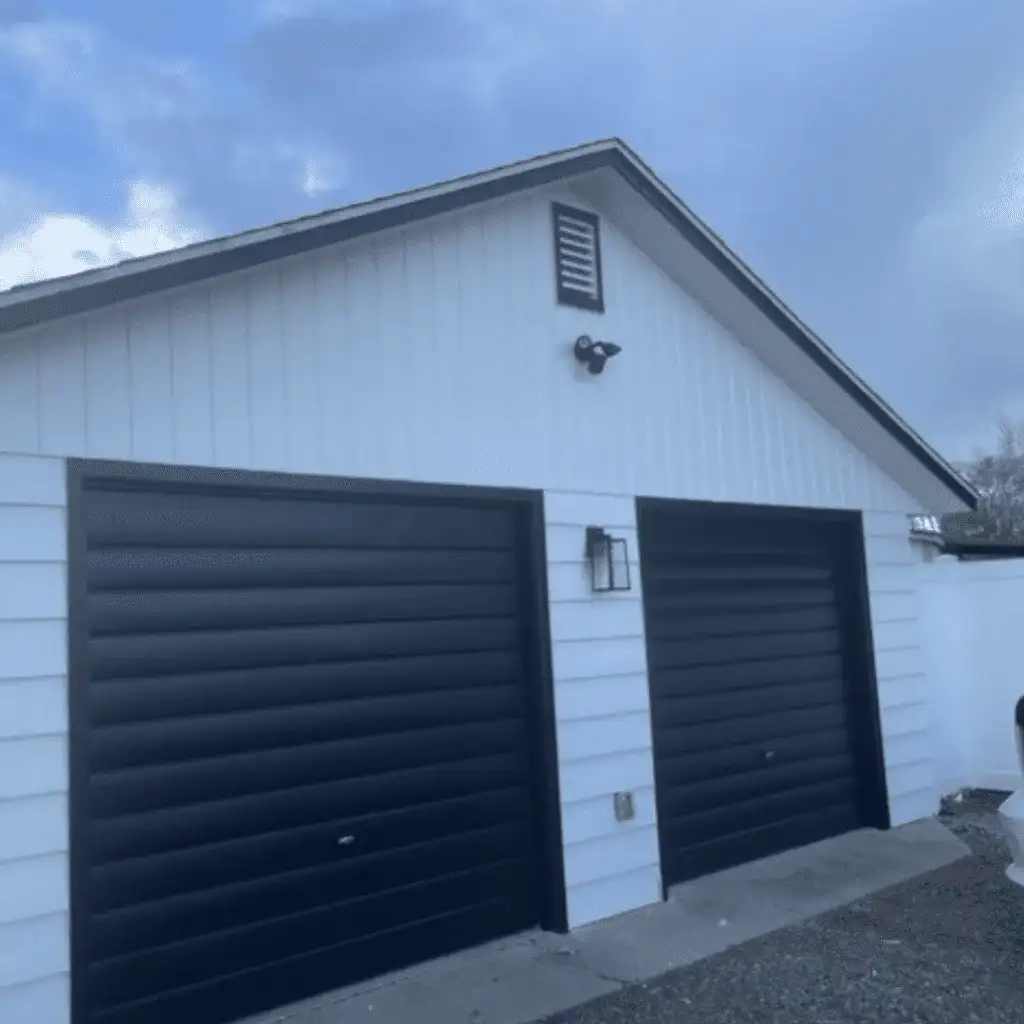After: the garage painted white with black garage doors