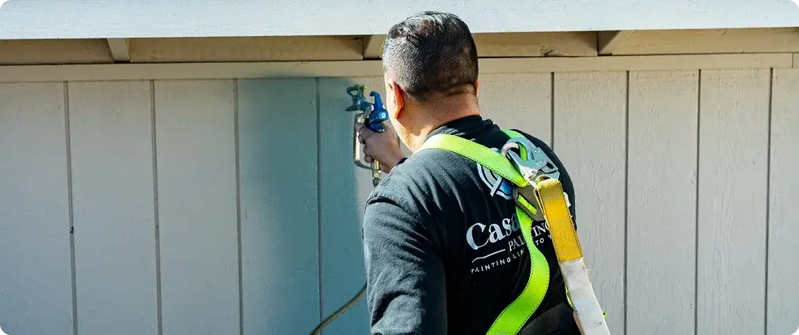 Casa Vida painter in a safety harness spraying vertical boards