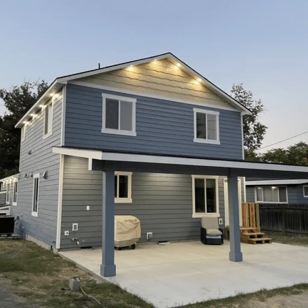 Back of a slate-blue two-story with a covered patio and deck steps