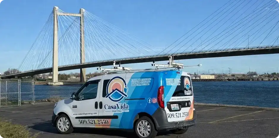Casa Vida van parked by the river with the Tri-Cities cable bridge behind it